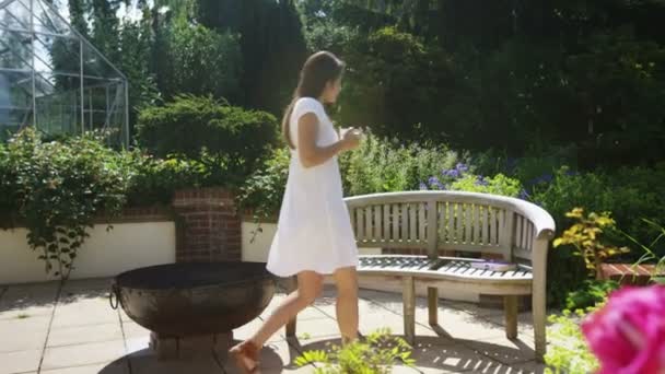 Woman relaxing with a drink in garden — Stock Video