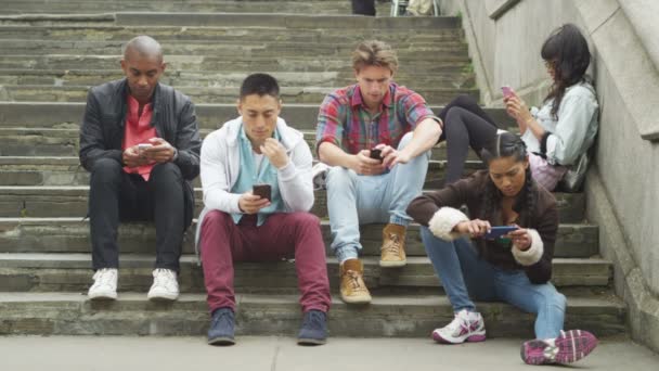 Друзья все смотрят на смартфоны — стоковое видео