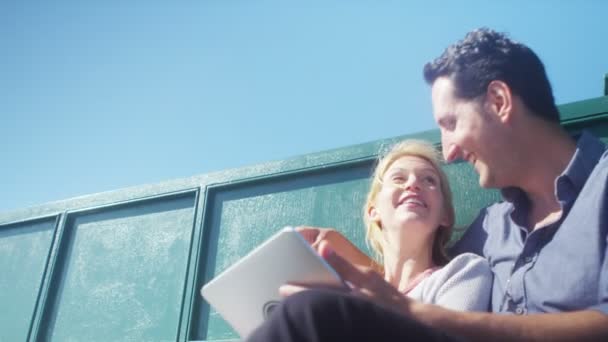 Casal com computador tablet relaxante no banco — Vídeo de Stock