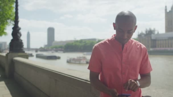 Homme avec téléphone portable debout près de la Tamise — Video