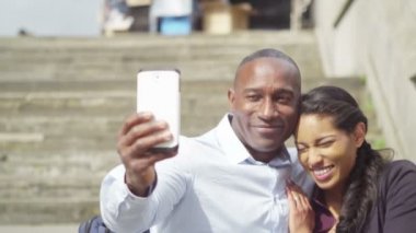 Çift akıllı telefonla selfie çekiyor.