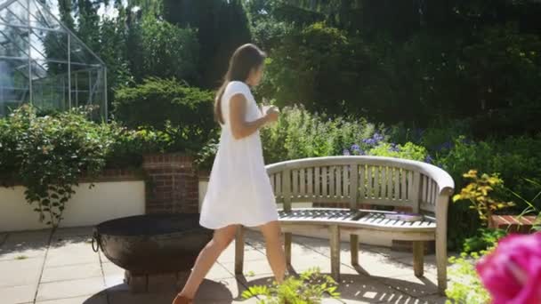 Vrouw ontspannen met een drankje in de tuin — Stockvideo