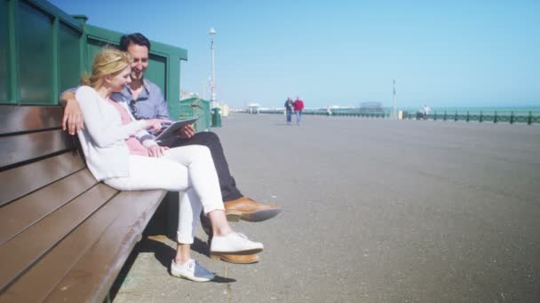 Couple with computer tablet relaxing on bench — Stock Video