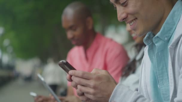 Amigos usando teléfonos inteligentes al aire libre — Vídeos de Stock