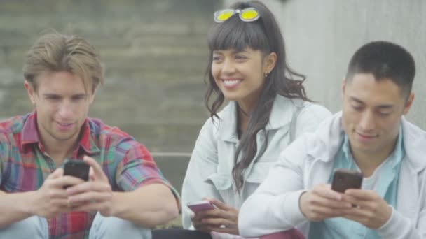 Amigos mirando a los teléfonos inteligentes al aire libre — Vídeo de stock