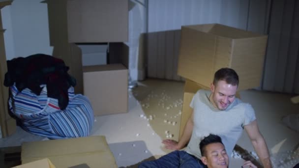 Pareja gay sentado entre cajas en casa — Vídeo de stock