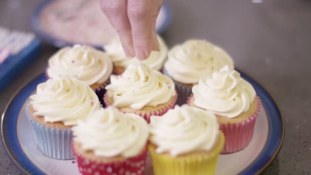 Hand streut Belag auf Cupcakes — Stockvideo