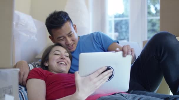 Пара с компьютером планшет лежит на полу — стоковое видео