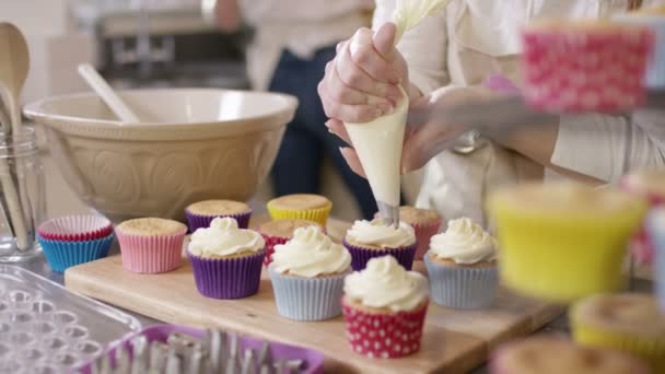 Vrouw leidingen crème op cupcakes — Stockvideo