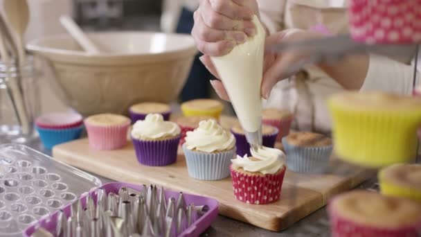 Γυναίκα σωληνώσεις κρέμας σε cupcakes — Αρχείο Βίντεο