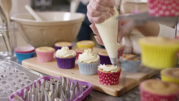 Γυναίκα σωληνώσεις κρέμας σε cupcakes — Αρχείο Βίντεο