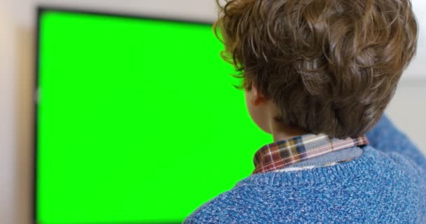 Мальчик смотрит телевизор с зеленым экраном — стоковое видео