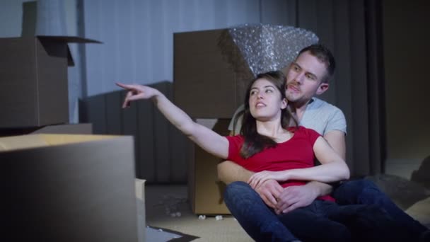 Пара сидит среди коробок — стоковое видео