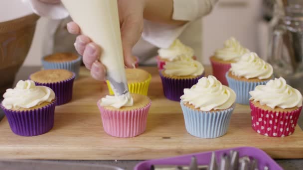 女性は、カップケーキの上にクリームを配管 — ストック動画