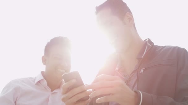 Друзья мужчины, использующие мобильные телефоны — стоковое видео