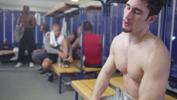 Exhausted man sitting in gym locker room — Stock Video
