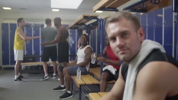 Усміхнений чоловік сидить у роздягальні спортзалу — стокове відео