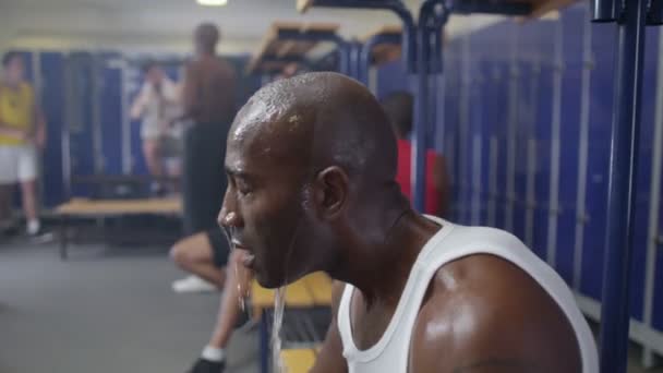Man in gym locker room rehydrating with water — Stock Video