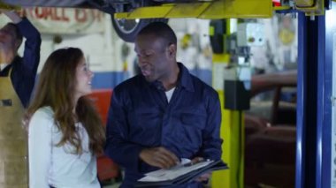 Müşteriye çalışmaları hakkında konuşurken araba tamircisi