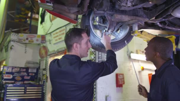 Mecánicos trabajando debajo de un coche — Vídeos de Stock