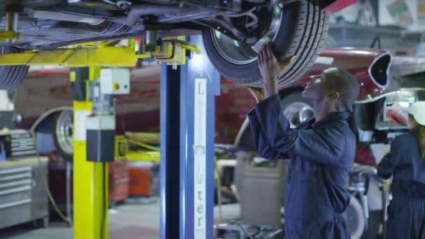 Mecánicos trabajando debajo de un coche — Vídeo de stock