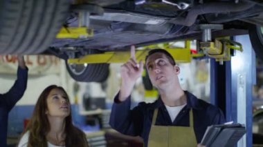 Müşteriye çalışmaları hakkında konuşurken araba tamircisi