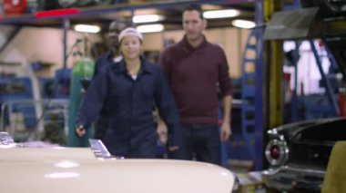 Müşteriye çalışmaları hakkında konuşurken araba mekaniği