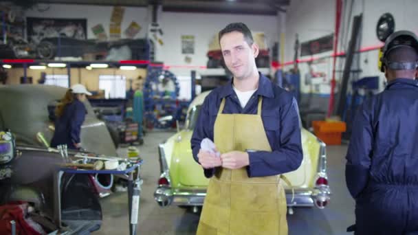 Улыбающийся механик в гаражной мастерской — стоковое видео