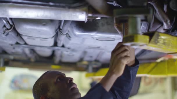 Mecánico trabajando debajo de un coche — Vídeos de Stock