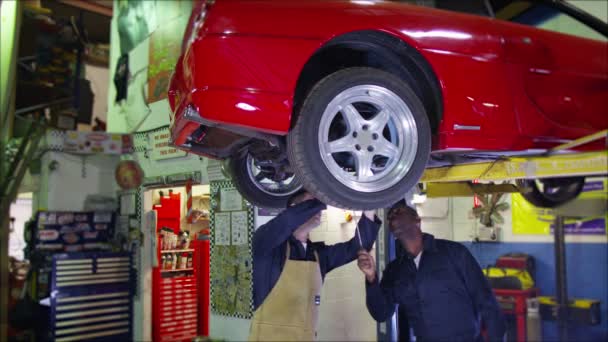 Mecánicos trabajando debajo de un coche — Vídeos de Stock