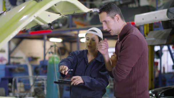 Mechanic in garage talking to customer — Stock Video