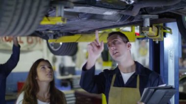 Müşteriye çalışmaları hakkında konuşurken araba tamircisi