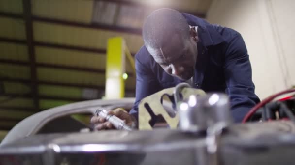 Механик, работающий над классическим автомобильным двигателем — стоковое видео