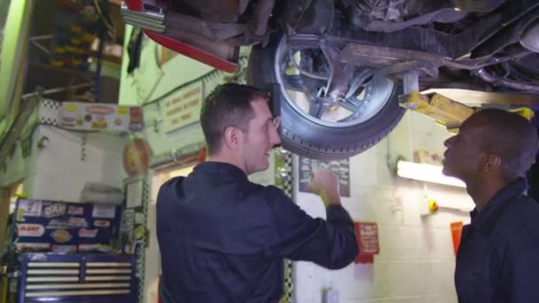 Mecánicos trabajando debajo de un coche — Vídeos de Stock
