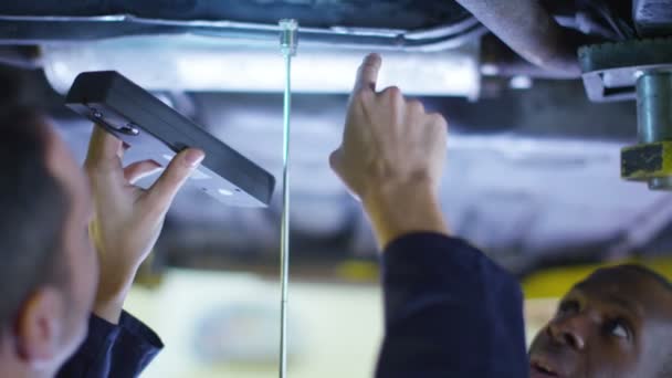 Mecánicos trabajando debajo de un coche — Vídeo de stock