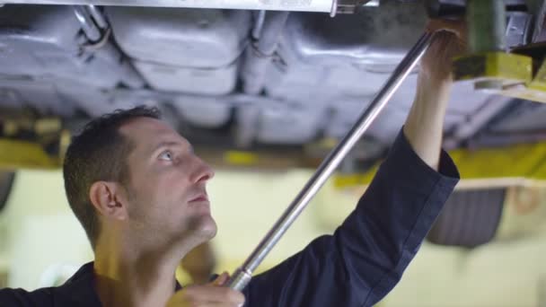 Mecánico trabajando debajo de un coche — Vídeos de Stock