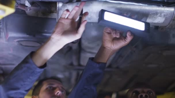Механики, работающие под машиной — стоковое видео