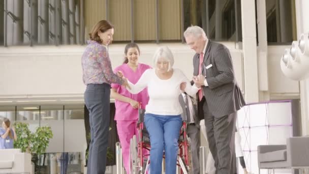 Medisch personeel helpen een patiënt in een rolstoel te staan — Stockvideo