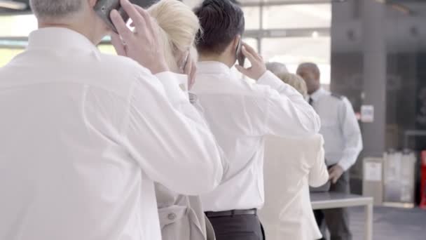 Mensen uit het bedrijfsleven op mobiele telefoons bij de veiligheidscontrole — Stockvideo