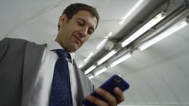 Zakenman met smartphone naar beneden roltrap — Stockvideo