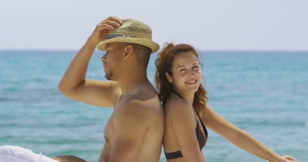 Paar sitzt Rücken an Rücken am Strand — Stockvideo