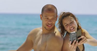 Çift bir cep telefonu ile sahilde rahatlatıcı