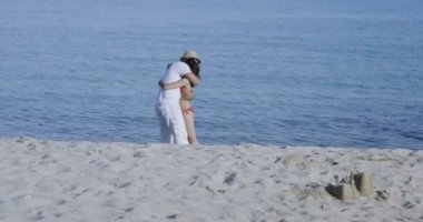 Kumsalda kucaklaşan bir çift.