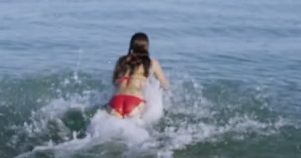 Woman running into the water for a swim — Stock Video