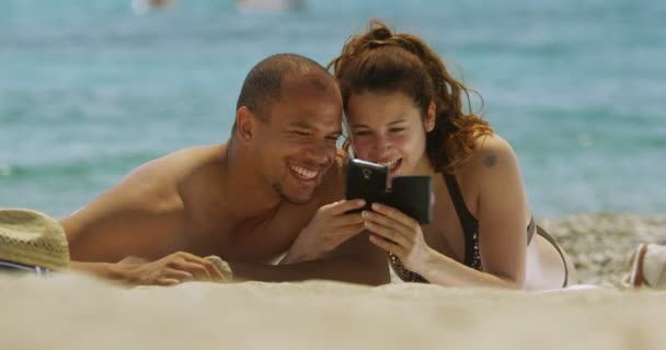 Para relaksujący na plaży z telefonem komórkowym — Wideo stockowe