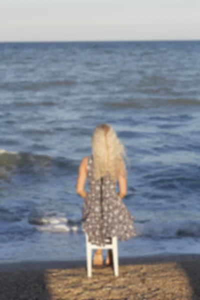 Sahil sandalye üzerinde oturan genç kadın bulanık resim — Stok fotoğraf