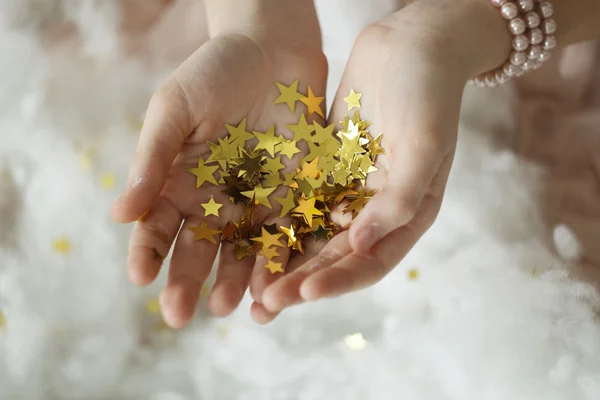 Woman's hands holding golden tinsel stars — Stock Photo, Image