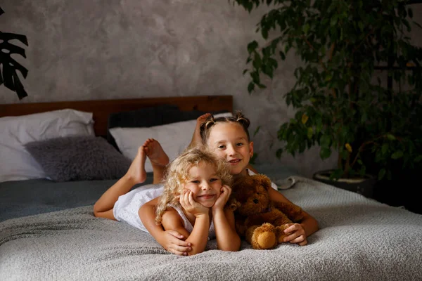 Duas Irmãzinhas Vestidos Brancos Deitados Cama Luz Dia Com Brinquedo — Fotografia de Stock