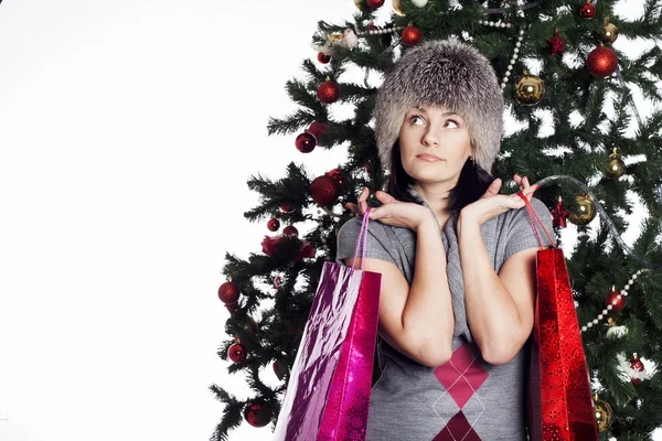 Jonge vrouw in de buurt van nieuwe jaar boom maakt winkelen — Stockfoto