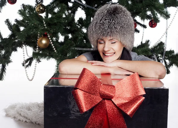 Mujer joven cerca de árbol de año nuevo con presente —  Fotos de Stock